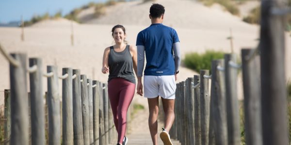 A couple enjoys jogging on a sunny beach boardwalk in Portugal, capturing a moment of fitness and leisure.